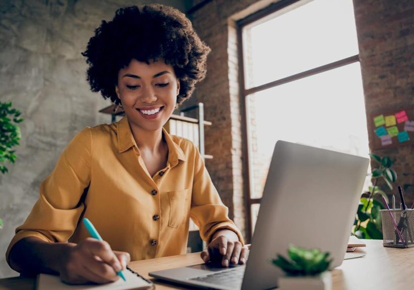 Photo of cheerful pretty cute nice girlfriend having, been employed to job as executive smiling toothily sitting at desktop with laptop noting down important information